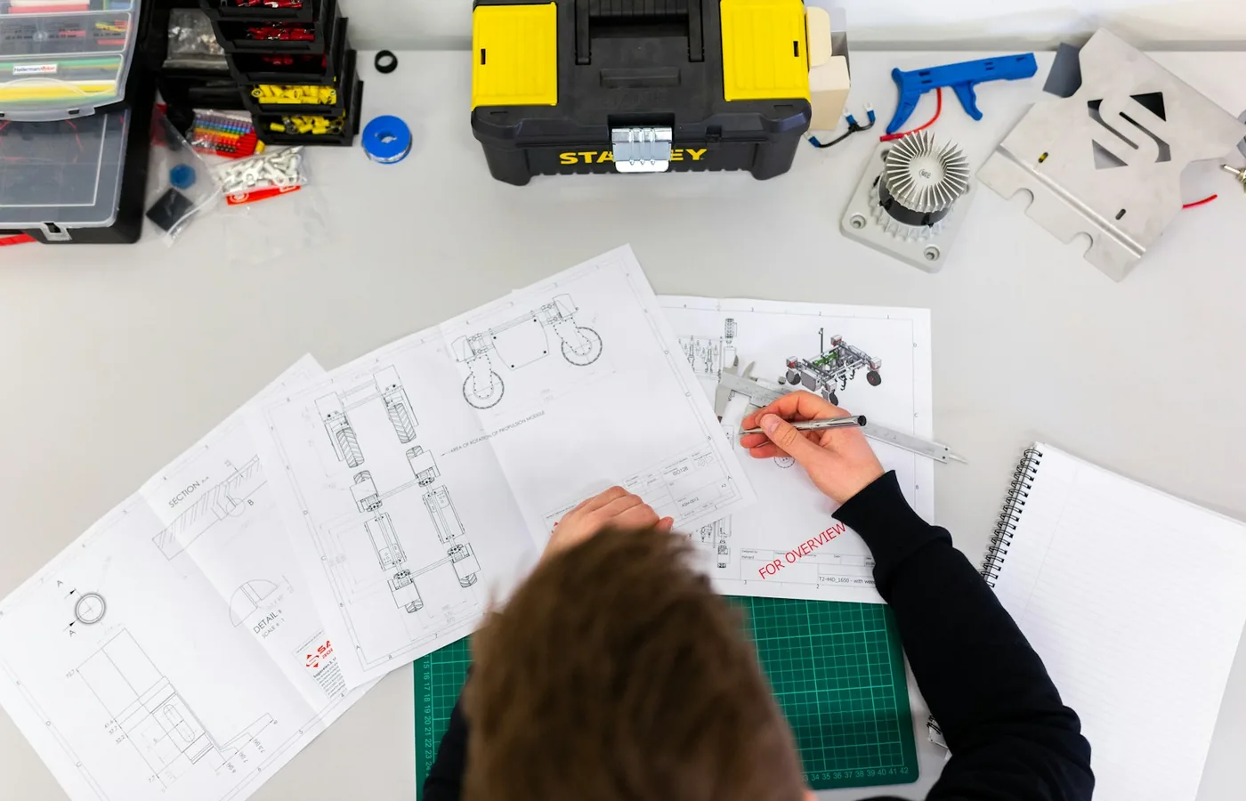 Engineer reviewing technical drawings, calipers, and scope documents for RFQ structuring